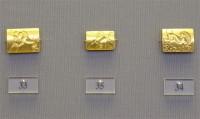 33, 34, 35. Gold seals with engraved scenes of a man fighting a lion, a lion in a rocky landscape, and a duel respectively.