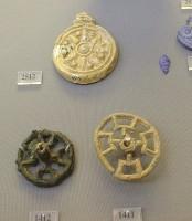1411, 1412, 2512. Bronze wheels of a North-European type with unusual crooked rays, which could be seals or sun symbols (1411, 1412); Glass female figurine and circular pendant with relief rosette imported from Mesopotamia. 14th-13th centuries BC (2512)