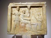 3075. Αναθηματικό ναόσχημο ανάγλυφο. Μάρμαρο λευκό. Βρέθηκε στο ιερό του Πυθίου Απόλλωνα στον αττικό δήμο της Ικαρίας (σημερινός Διόνυσος). 330-320 π.Χ.