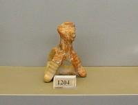 1204. Clay figurine of a seated dog with a hole at the neck (pendant).