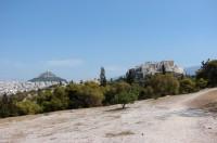 Pnyx Archaeological Site: The Acropolis rock, the Areopagus Hill with visitors on it and the imposing Hill of Lycabettus